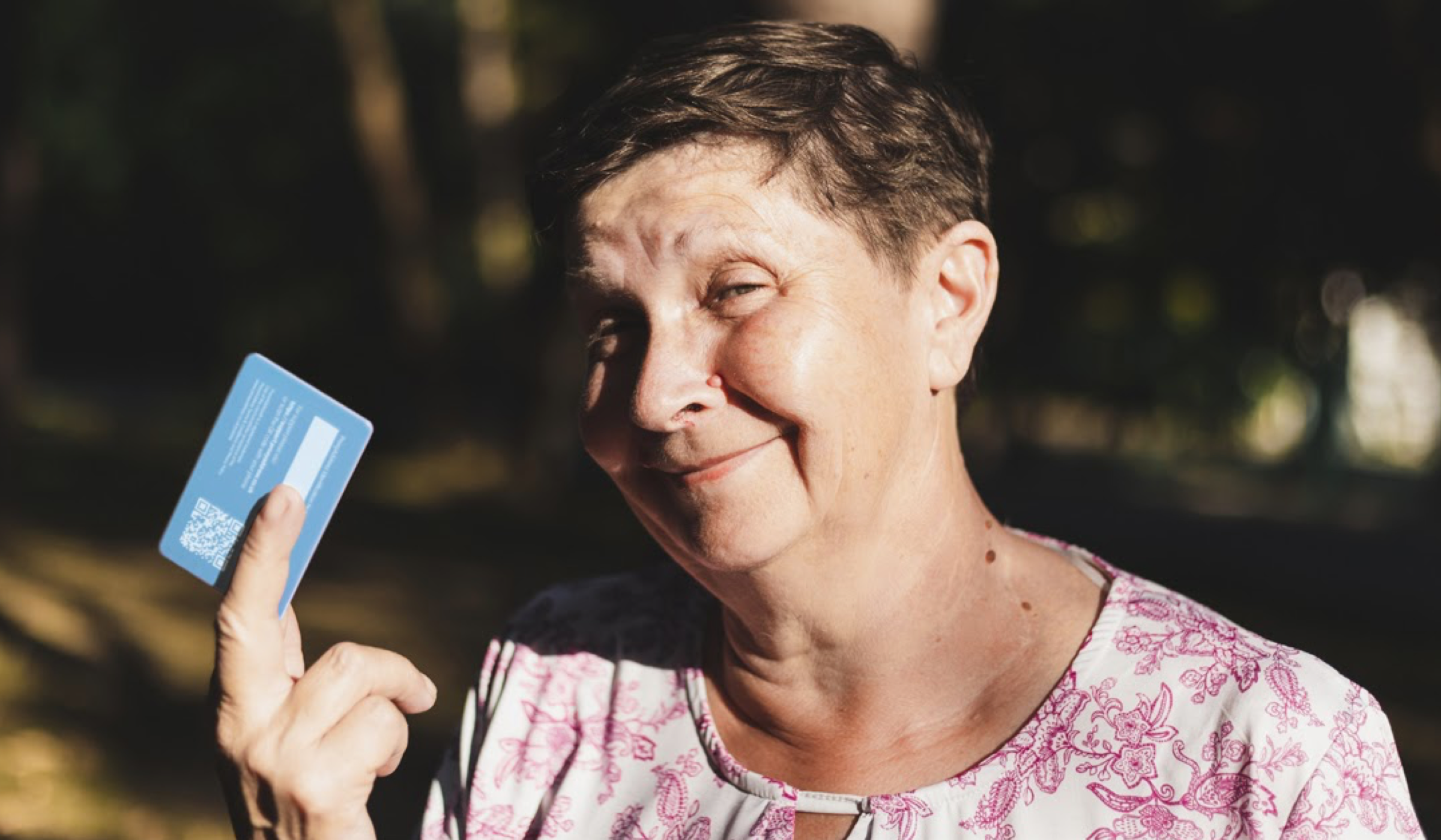 Smiling woman holds up blue ProxyAddress card